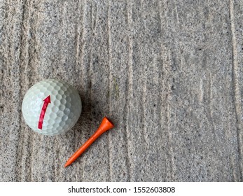 A Golf Ball And Tee On Concrete Floor