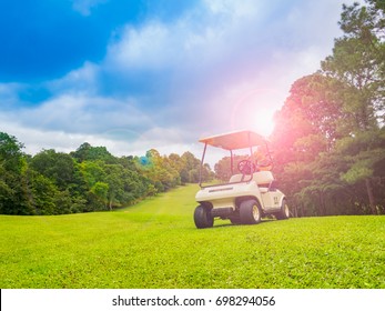 Golf Car Or Cart On Beautiful Fairway On Layout Of Golf Course. Player See Beauty Of Sky And Cloud With Green Grass And Large Trees Litter. Course With Beautiful Light In Sunset And Sunshine For Play