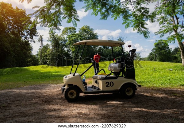 Golf car on the beautiful golf course in the evening\
golf course with fresh green grass with blurry background golfer\
playing golf. 
