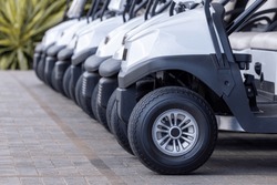  Golf Cars In A Row Outdoors On A Golf Course. A Row Of Empty Golf Carts On A Course. Golf Course Carts Cars At Luxury Resort Sport Venue.All Lined Up Ready For A Tournament On A Course. 
