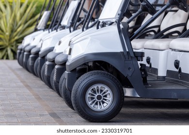  Golf cars in a row outdoors on a golf course. A row of empty golf carts on a course. golf course carts cars at luxury resort sport venue.All lined up ready for a tournament on a course.  - Powered by Shutterstock