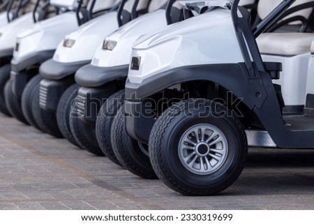  Golf cars in a row outdoors on a golf course. A row of empty golf carts on a course. golf course carts cars at luxury resort sport venue.All lined up ready for a tournament on a course. 