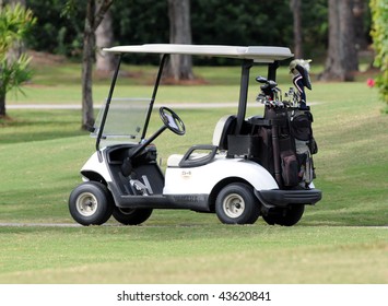 Golf cart loaded with clubs on a course.