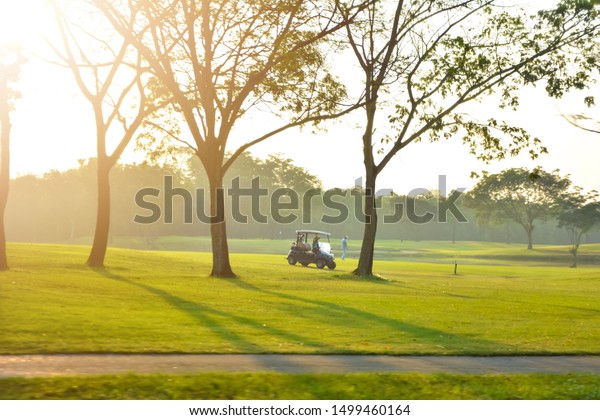 Golf\
cart park in front of green golf court,\
landscape.