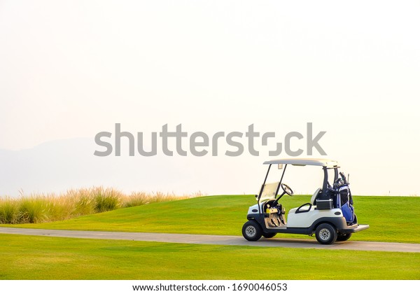 Golf carts on the\
green yard in the morning.