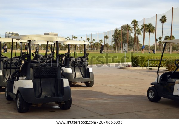 Golf carts\
parked outside near the golf course.\
