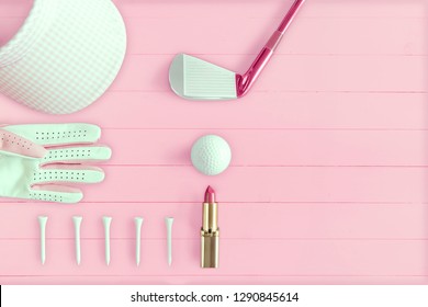 Golf club, golf ball and golf glove on pink wooden base from above, ladies day