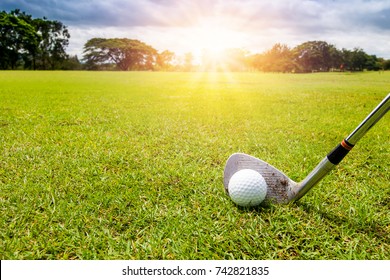 Golf Club And Golf Ball In Grass In Sunrise.