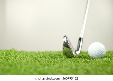 Golf club and golf ball on green grass