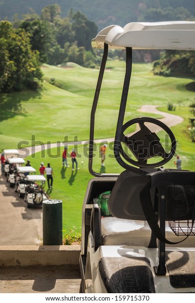 Golf club cars at golf field with golfers are on\
started point