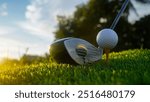 Golf clubs and balls on a green lawn in a beautiful golf course with morning sunshine. Close up of golf equipment on green grass.                                 