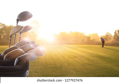 Golf Clubs Drivers And Golfer Putting Golf Ball On The Green  Over Beautiful Golf Course At The Sunset, Sunrise Time. , Morning Time 