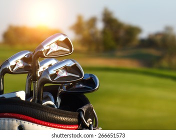 Golf clubs drivers over green field background. Summer sunset