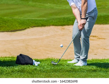 Golf Coach Hitting Golf Ball. No Face, Sand Splashing.