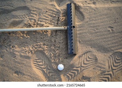 Golf concept. Golf ball and rake sand on bunker in beautiful golf course at sunset background.                                 - Powered by Shutterstock