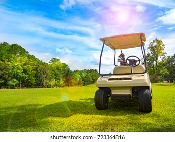 Golf Concept. Golf Cart Or Club Car On Beautiful Fairway On Layout Of Golf Course. We See Beauty Of Layout And Fairway With Green Grass And Large Tree. Golf Course With Beautiful Light In Sunset