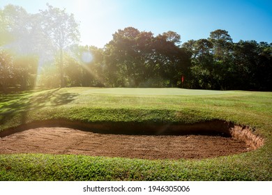 Golf course for golfer playing sport, bunker sand before green golf, lawn fairway and layout landscape course, light rays of sunny of sunrise morning is beauty, green grass and forest on hills