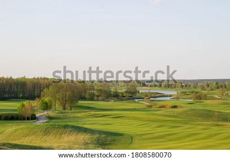 Similar – A tranquil aerial view of a lush golf course fairway, bathed in the warm glow of sunset. Ideal for themes of relaxation, nature, and sports, this image captures the peaceful beauty of the golfing experience.