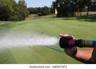 A Golf Course Maintenance Worker Waters A Golf Green