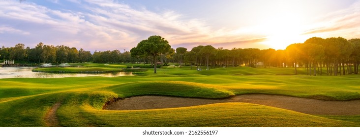 Golf course at sunset with beautiful sky and sand trap. Scenic panoramic view of golf fairway with bunker. Golf field with pines - Shutterstock ID 2162556197
