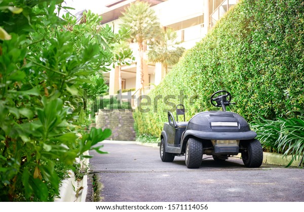 Golf Electric Cart  On The Paving Road To\
The Hotel. Black Empty Shuttle Electro\
Car.