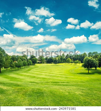 Golf field and blue cloudy sky. Beautiful landscape with green grass. Retro style toned picture