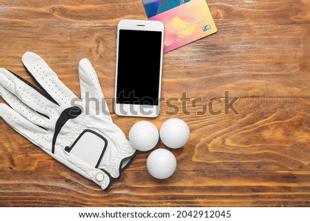 Golf glove, mobile phone and credit cards on wooden background. Concept of sports bet