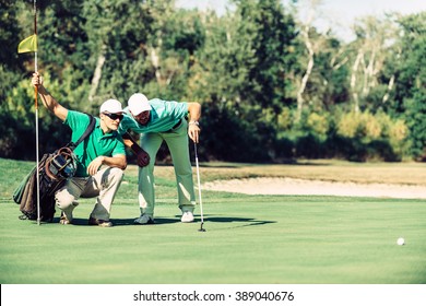 Golf. Golfer reading the green with his caddy