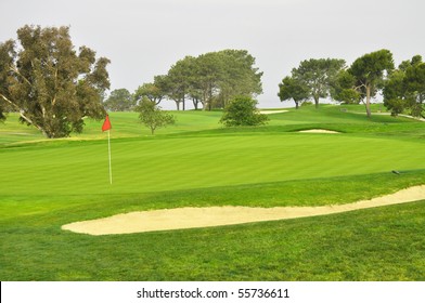 Golf Green With Red Flag And Sand Trap.