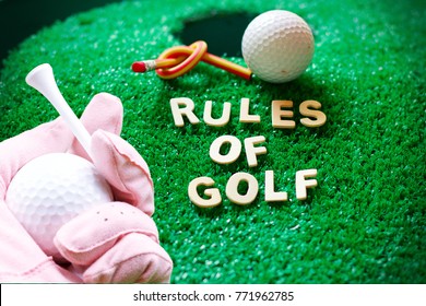 Golf I  Hand With Rules Of Golf And Golf Ball On Green Grass