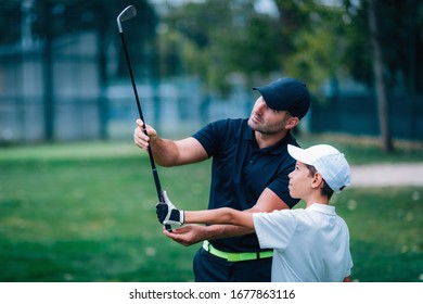 Golf Instructor Adjusting Young Boy’s Grip 