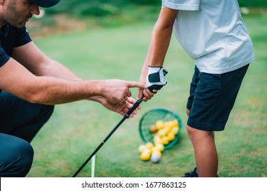 Golf Instructor Adjusting Young Boy’s Grip 