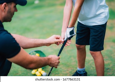 Golf Instructor Adjusting Young Boy’s Grip 