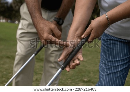 Golf instructor teaching how to a female apprentice to adjust her grip