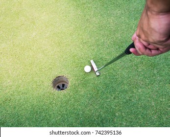 Golf Man Grab The Putter To Hit The Golf To The Hole On Green. POV Concept