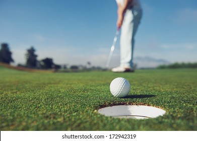 Golf man putting on green for birdie while on vacation