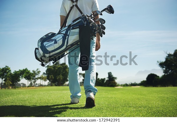 Golf\
man walking with shoulder bag on course in\
fairway