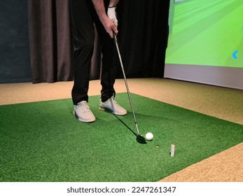 Golf player playing golf indoors on golf simulator closeup. Driving range with screen for golf and golfer legs - Shutterstock ID 2247261347