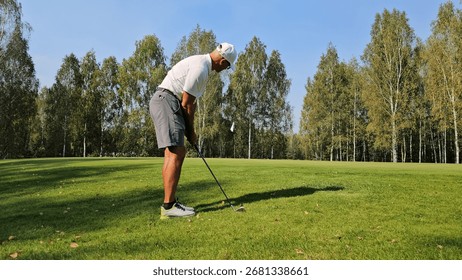 Golf player practicing swing on a sunny day in a lush green golf course surrounded by trees
