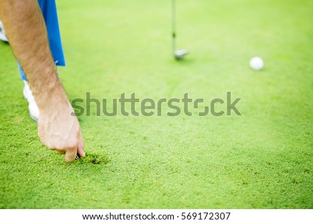 Golf player repairing divot on a green grass surface