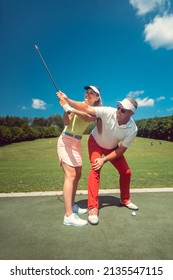 Golf Pro Teaching A Woman Student Of The Driving Range