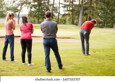 Golf Professional Demonstrating Shot On Fairway To Group Of Golfers During Lesson