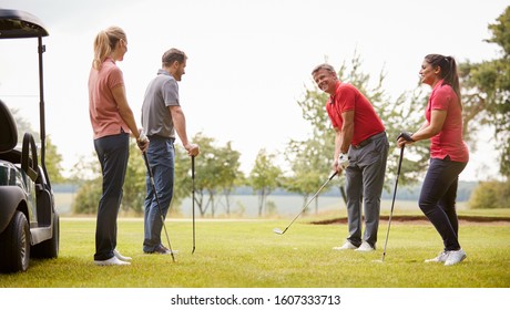 Golf Professional Demonstrating Shot On Fairway To Group Of Golfers During Lesson