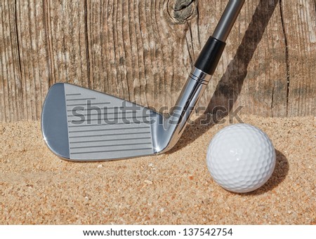 Golf stick and ball support wooden close-up on the sand.