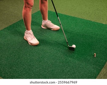 Golf swing preparation at an indoor putting green with a player ready to hit the ball - Powered by Shutterstock