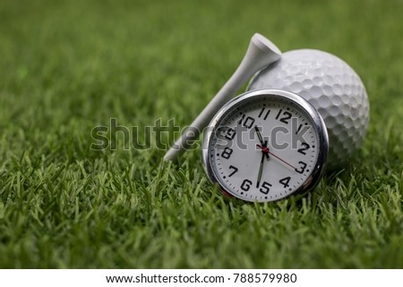 Golf time with golf ball and clock on green grass.