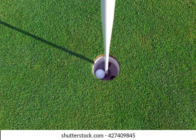 Golfball With Flagstick And Hole On Putting Green On Golf Course 