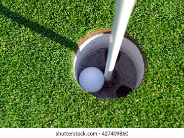 Golfball with Flagstick and hole on putting green on golf course 