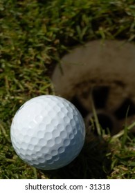 Golfball Laying On The Edge Of A Hole. Narrow DOF, Focus On The Ball.