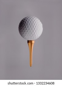 Golfball On Top Of Golden Golf Tee, Grey Background